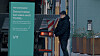 Person ved en ladestasjon for elbil ved siden av en grønn infosøyle.
